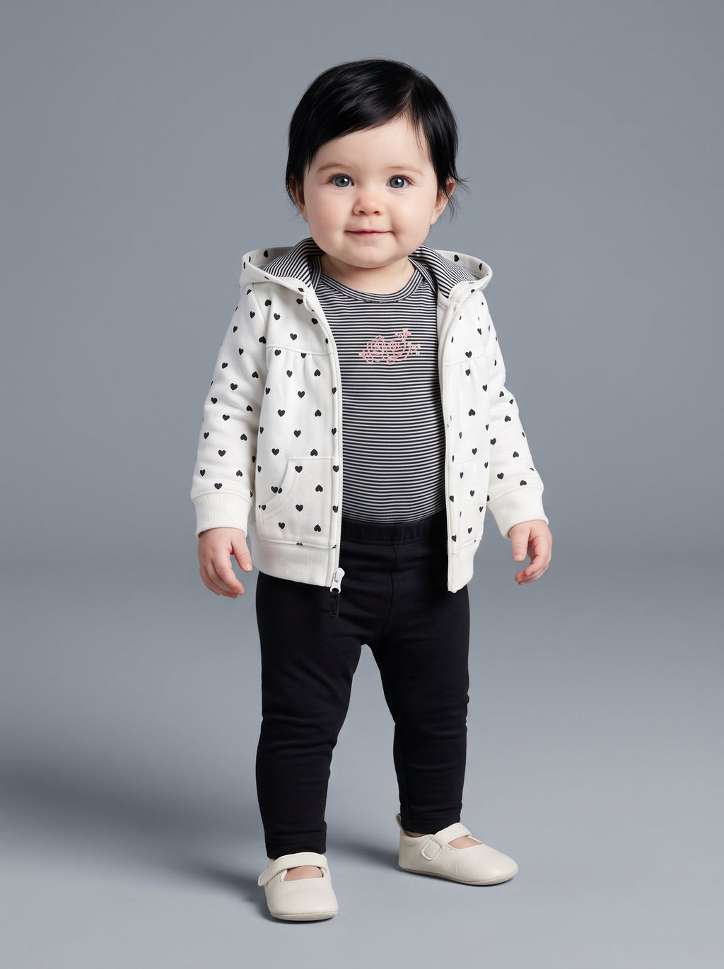 Bebé niña vistiendo conjunto EmpiBy de 3 piezas: chaqueta blanca con corazones, body a rayas y legging negro.