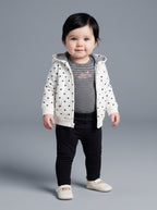 Bebé niña vistiendo conjunto EmpiBy de 3 piezas: chaqueta blanca con corazones, body a rayas y legging negro.
