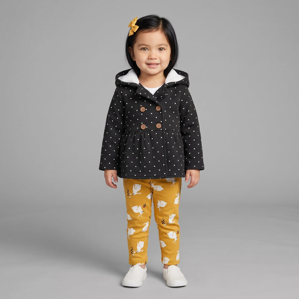 Conjunto EmpiBy de 3 piezas para niña: chaqueta negra con lunares, body blanco y pantalón mostaza con conejitos.