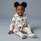Bebé niña sonriente con conjunto EmpiBy de tres piezas: chaqueta y pantalón con estampado floral azul y gris claro.