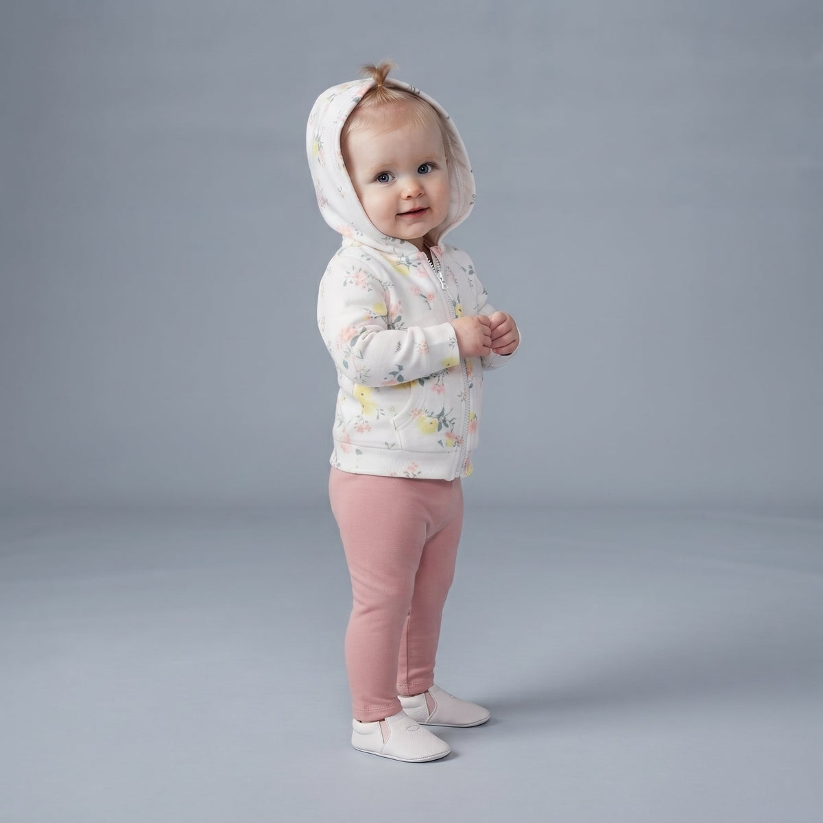 Bebé niña vistiendo conjunto EmpiBy de tres piezas: chaqueta con capucha floral, body blanco y leggings rosa liso.