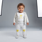 Bebé niña sonriente vistiendo conjunto EmpiBy de tres piezas: chaqueta gris con corazones, body blanco y leggings.