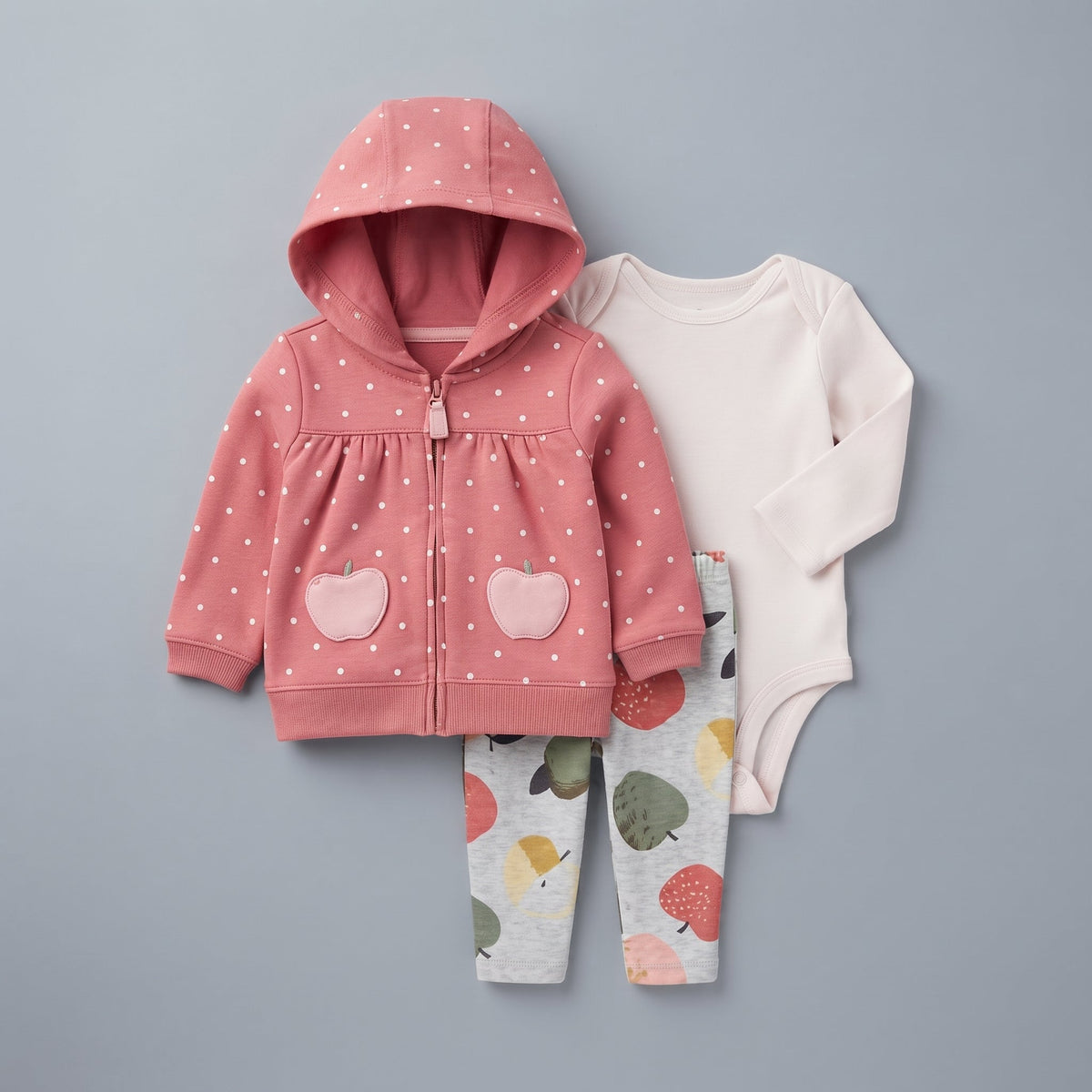 Conjunto EmpiBy de 3 piezas para bebé niña: chaqueta rosa con lunares, body marfil y pantalón gris con manzanas.