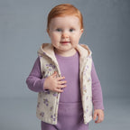 Bebé niña vistiendo conjunto EmpiBy de 3 piezas: chaqueta floral con capucha, body y pantalón morado acanalado.
