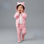 Bebé niña sonriente vistiendo conjunto EmpiBy de 3 piezas: chaqueta rosa con lunares y orejitas, body y pantalón