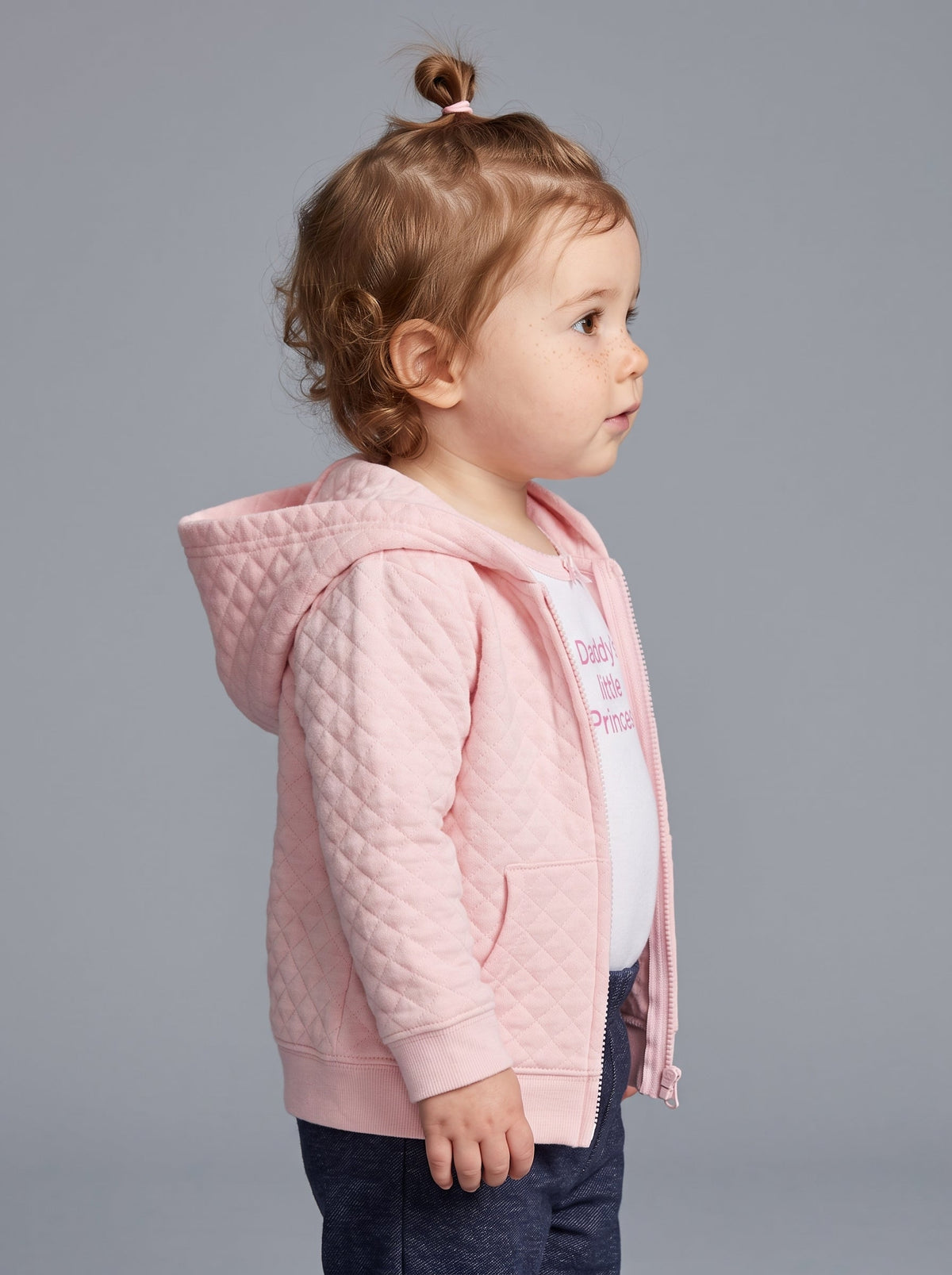 Niña pequeña con conjunto EmpiBy de 3 piezas: chaqueta rosa acolchada con capucha, body blanco y pantalón azul oscuro.