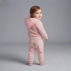 Bebé niña vistiendo conjunto EmpiBy de tres piezas rosa con chaqueta de capucha con orejitas y pantalón con osito