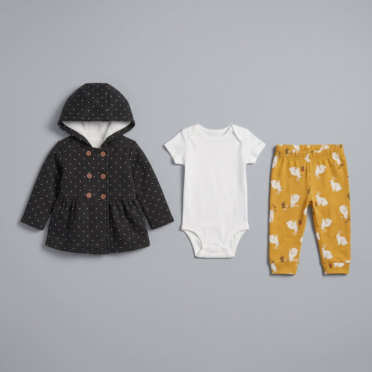 Conjunto de 3 piezas EmpiBy para bebé niña: chaqueta negra con lunares, body blanco y pantalón mostaza con conejitos.