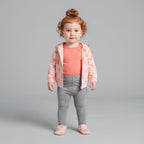 Niña pequeña vistiendo conjunto EmpiBy de tres piezas: chaqueta rosa con melocotones, body salmón y pantalón gris.