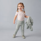 Niña pequeña con conjunto EmpiBy de tres piezas: body floral, pantalón verde salvia y sudadera con volantes.