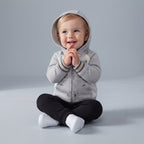Bebé con conjunto EmpiBy de 3 piezas: chaqueta gris con capucha de osito, body estampado y pantalón negro.