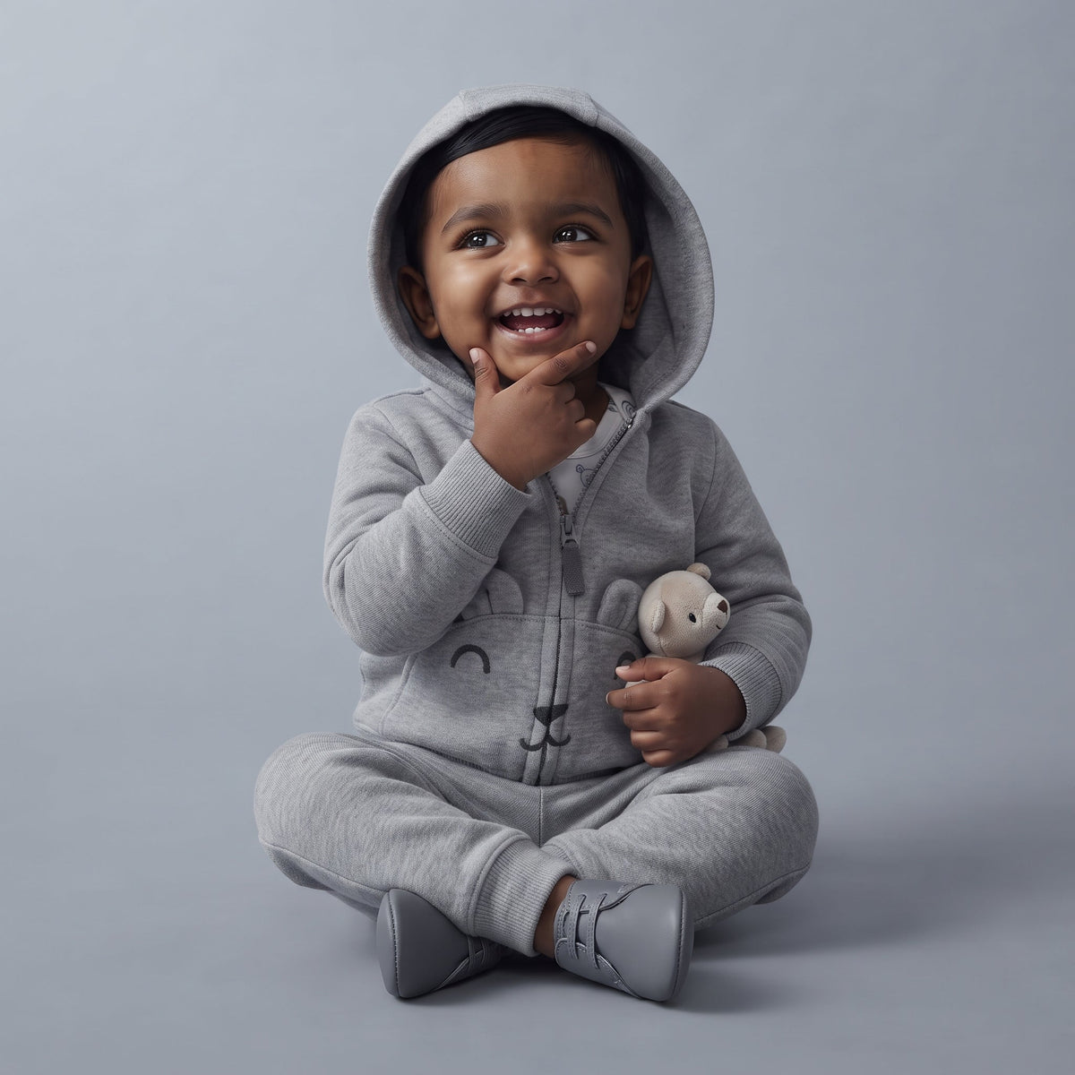 Bebé sonriente con conjunto EmpiBy de tres piezas gris, chaqueta con capucha de osito y pantalón cómodo