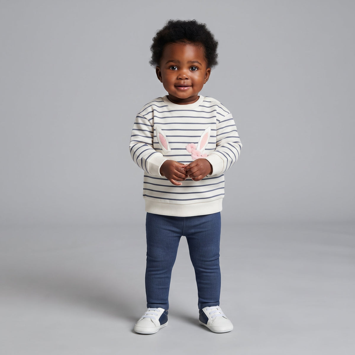 Bebé con conjunto EmpiBy de sudadera a rayas con orejas de conejo y legging denim azul, estilo casual y cómodo.