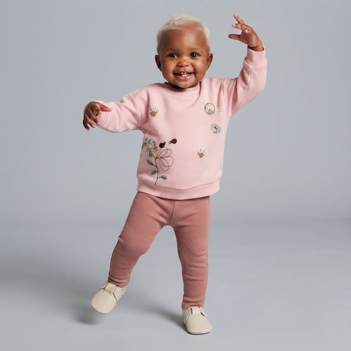 Bebé sonriente con conjunto EmpiBy de sudadera rosa con flores y abejas bordadas y leggings acanalados terracota