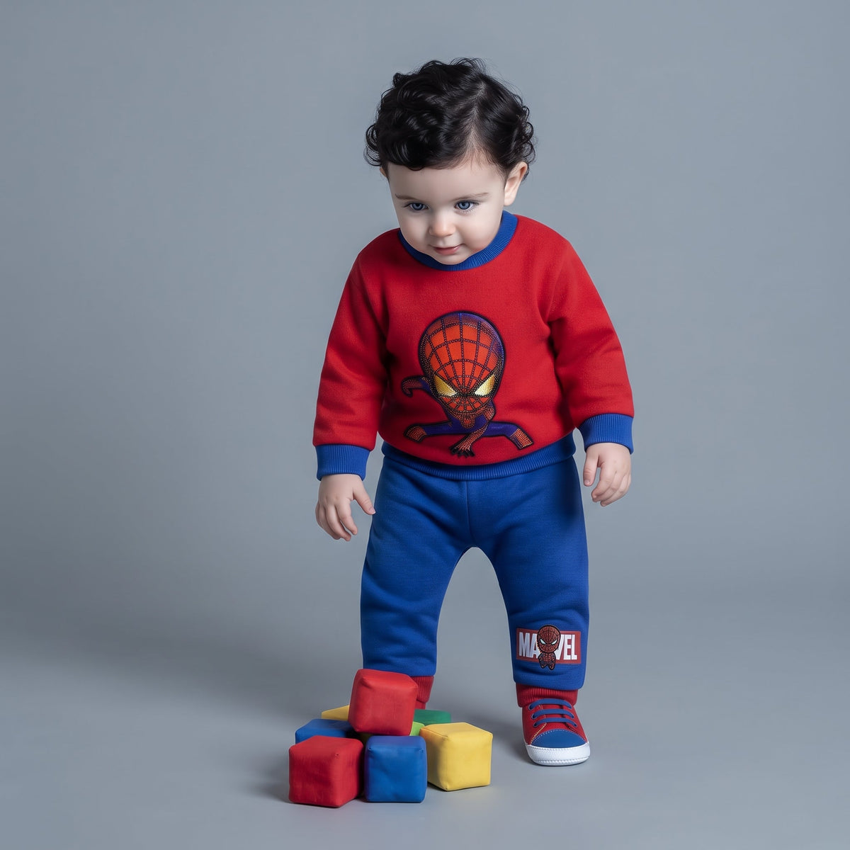 Bebé con conjunto de dos piezas EmpiBy de Spider-Man, sudadera roja y pantalón jogger azul con bloques de colores.