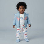 Bebé con conjunto EmpiBy de 3 piezas: chaqueta azul con volantes, body blanco con dinosaurio y pantalón estampado.