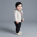Bebé niña vistiendo conjunto EmpiBy de 3 piezas: chaqueta blanca con corazones, body a rayas y legging negro.