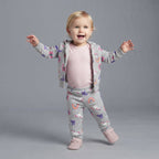 Bebé niña vistiendo conjunto EmpiBy de tres piezas gris con estampado de unicornios, arcoíris y body rosa de rayas.