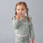 Niña pequeña vistiendo conjunto EmpiBy de tres piezas en verde salvia con sudadera de volantes y bordado floral