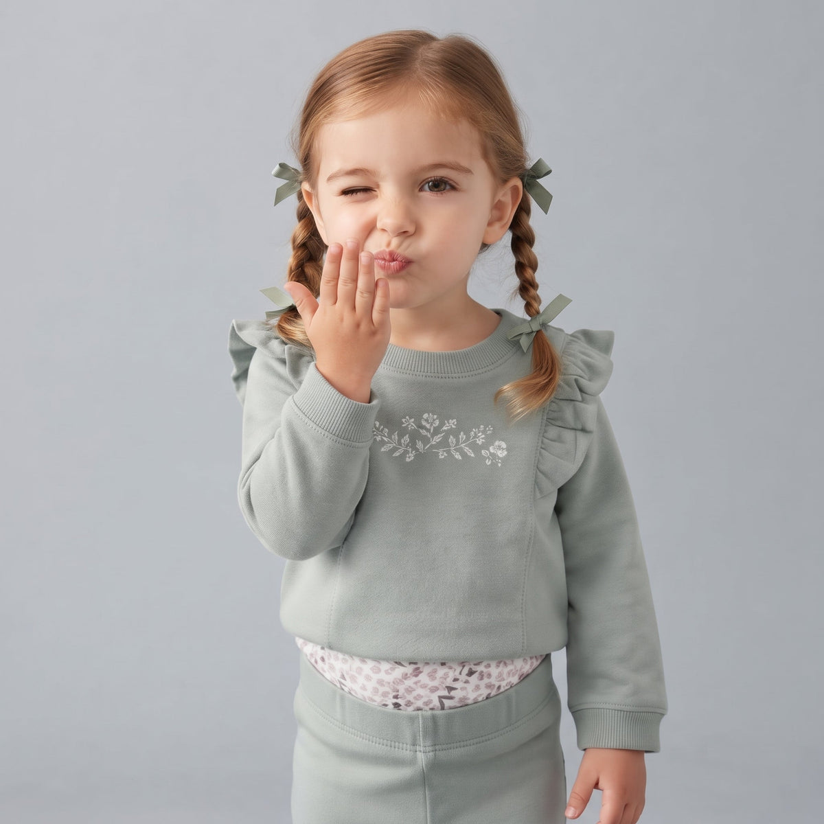 Niña pequeña vistiendo conjunto EmpiBy de tres piezas en verde salvia con sudadera de volantes y bordado floral