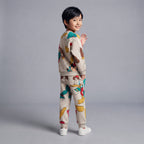 Niño sonriente vistiendo conjunto EmpiBy beige de dos piezas con estampado de Mickey y Donald estilo baseball