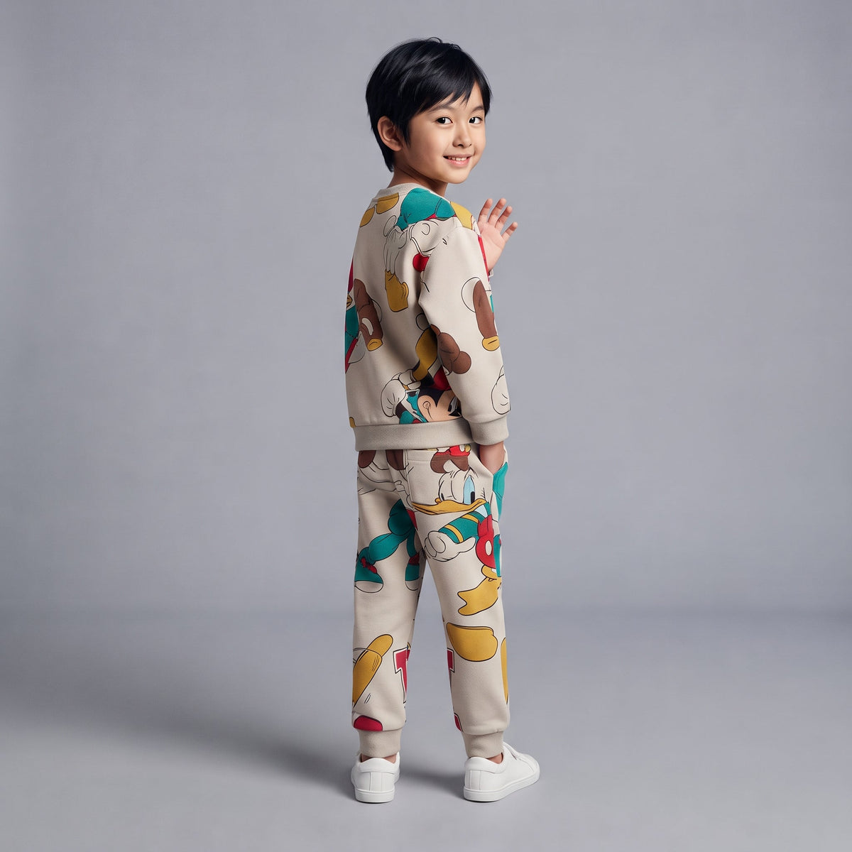 Niño sonriente vistiendo conjunto EmpiBy beige de dos piezas con estampado de Mickey y Donald estilo baseball