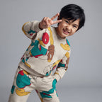 Niño sonriente vistiendo conjunto EmpiBy beige de dos piezas con estampado de Donald y Mickey estilo baseball