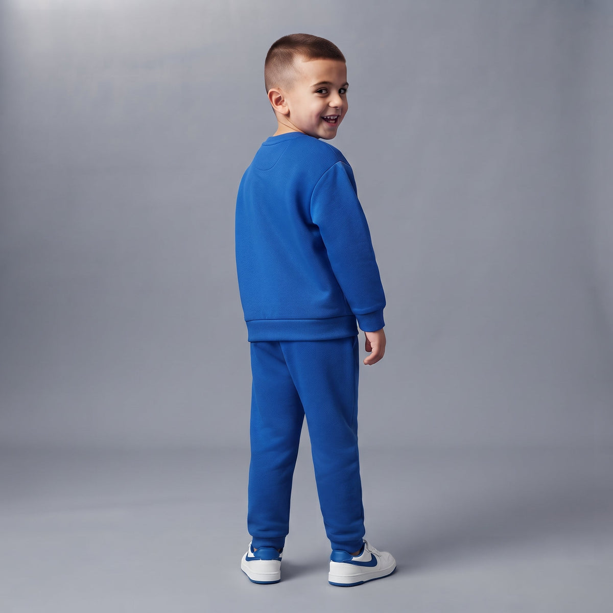Niño vistiendo conjunto deportivo azul EmpiBy de dos piezas con sudadera y pantalón jogger, vista de espaldas