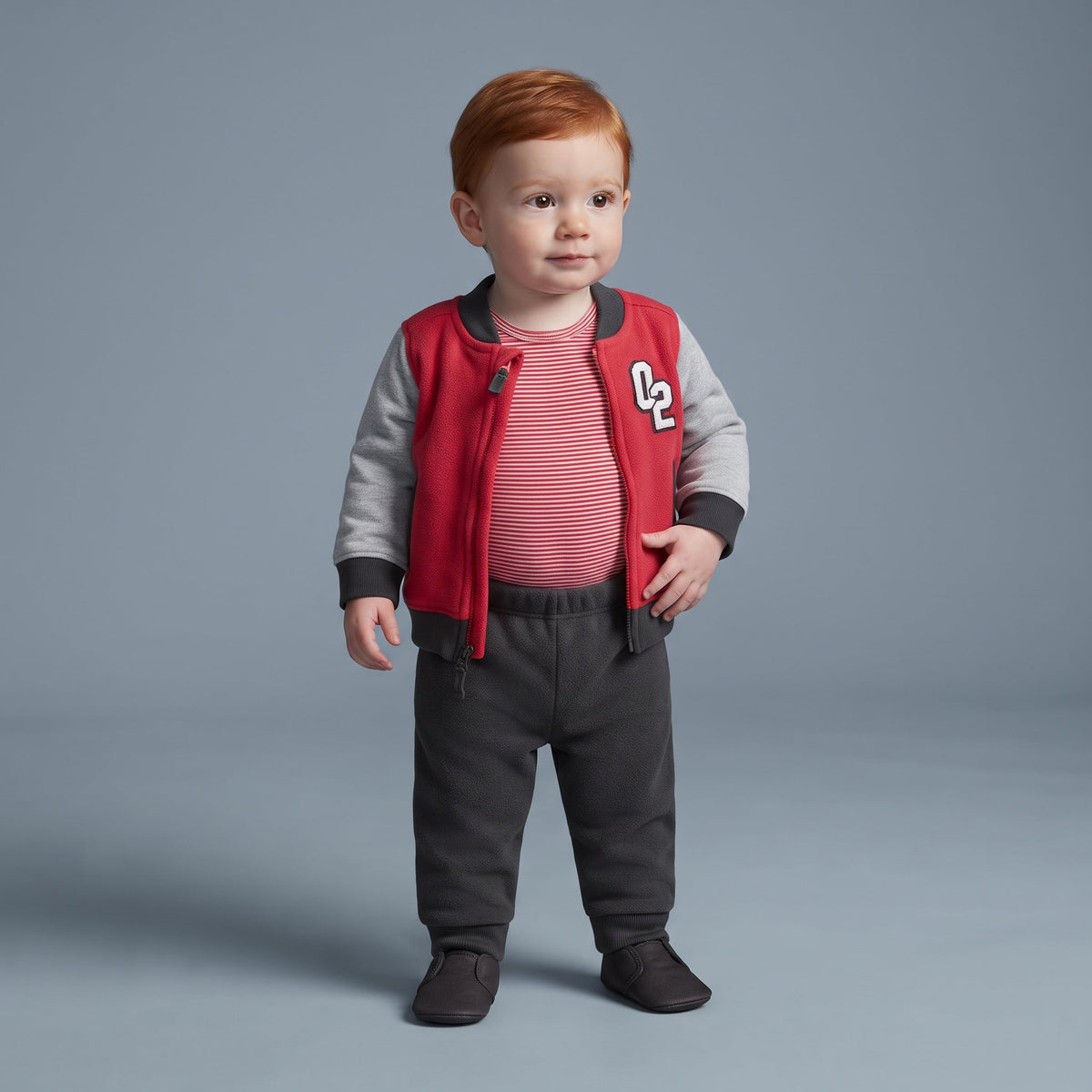 Conjunto deportivo EmpiBy de 3 piezas para bebé niño con chaqueta bomber roja, body a rayas y pantalón gris oscuro.