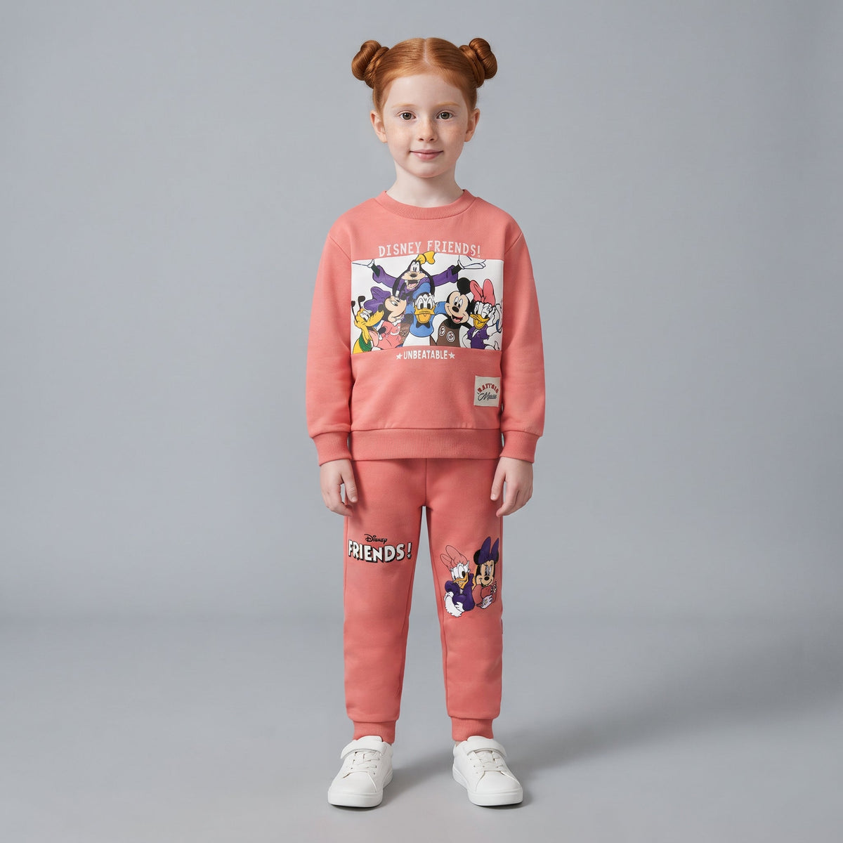 Niña vistiendo conjunto EmpiBy de dos piezas color coral con estampado de personajes Disney Friends y jogger a juego.