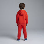 Niño de espaldas vistiendo conjunto deportivo rojo de dos piezas de EmpiBy con sudadera con capucha y pantalón jogger
