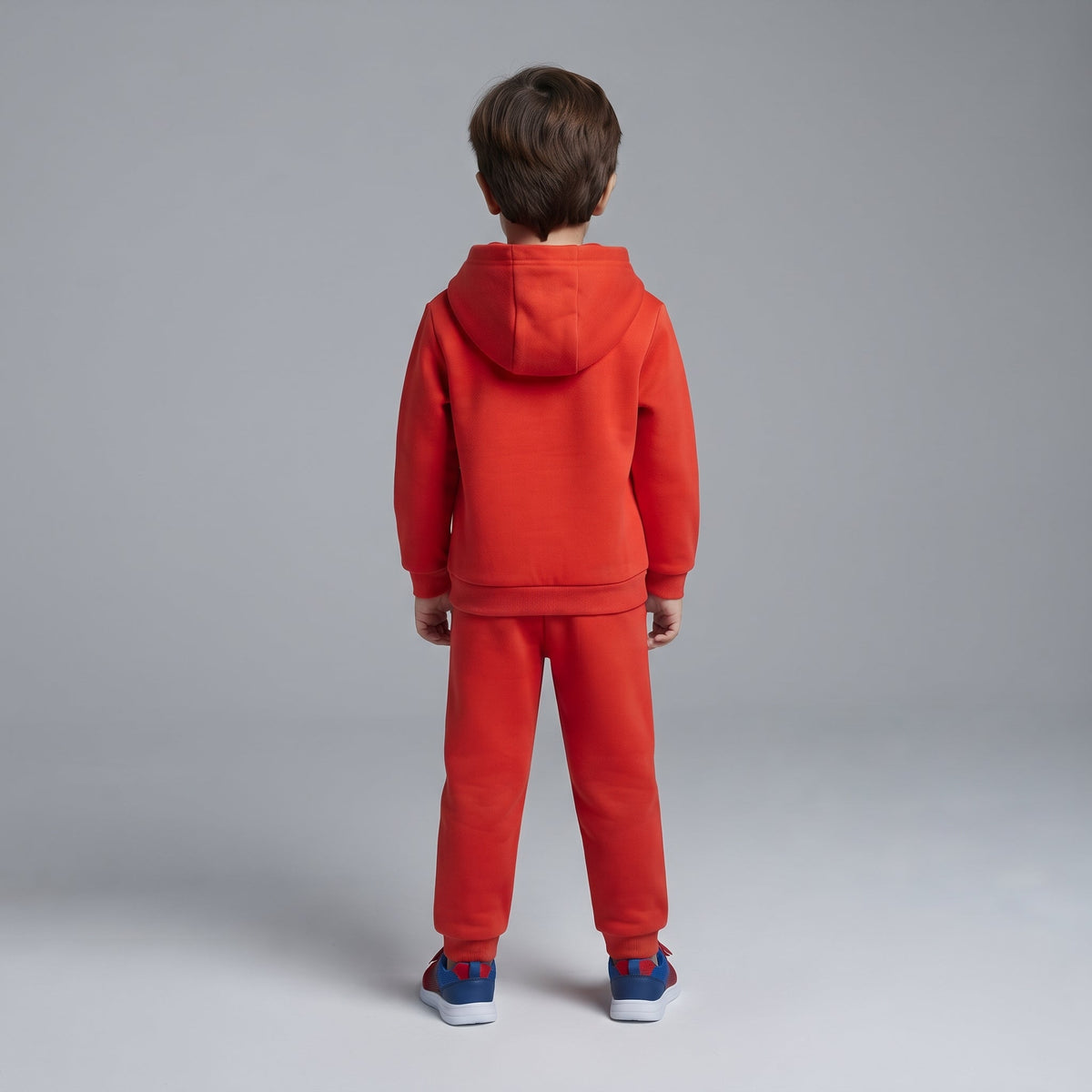 Niño de espaldas vistiendo conjunto deportivo rojo de dos piezas de EmpiBy con sudadera con capucha y pantalón jogger