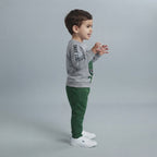 Niño vistiendo conjunto EmpiBy de sudadera gris con estampado de dinosaurio y pantalón verde cómodo