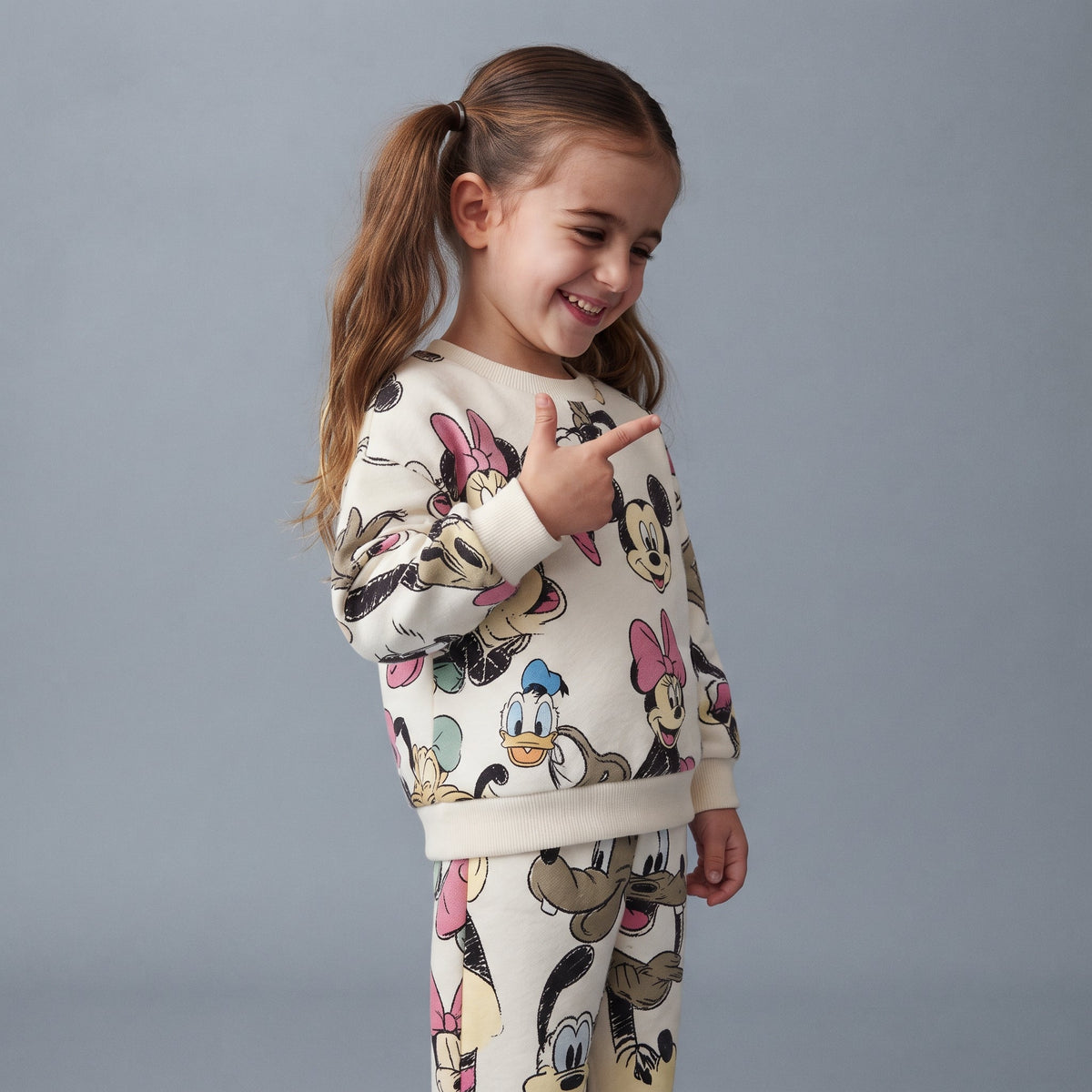 Niña sonriente vistiendo conjunto EmpiBy de dos piezas blanco con estampado de Minnie, Mickey y sus amigos de Disney