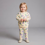 Niña pequeña vistiendo conjunto EmpiBy de dos piezas color crema con estampado de tulipanes púrpuras y hojas verdes