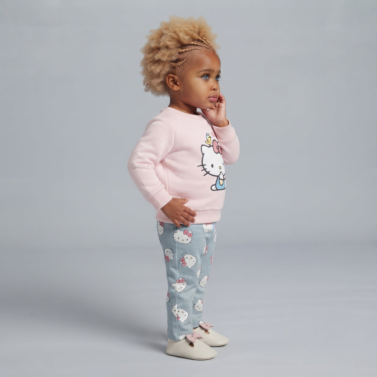 Niña pequeña vistiendo conjunto EmpiBy de suéter rosa con Hello Kitty y pantalón gris estampado de Hello Kitty