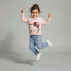 Niña saltando con conjunto EmpiBy de sudadera rosa Hello Kitty y jeans con bordados de personajes Sanrio