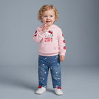 Niña pequeña vistiendo conjunto EmpiBy de sudadera rosa con Hello Kitty y jeans de mezclilla estampados.