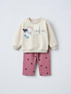 Conjunto EmpiBy de sudadera crema con estampado de Hello Kitty y pantalón rosa viejo con corazones negros para niña