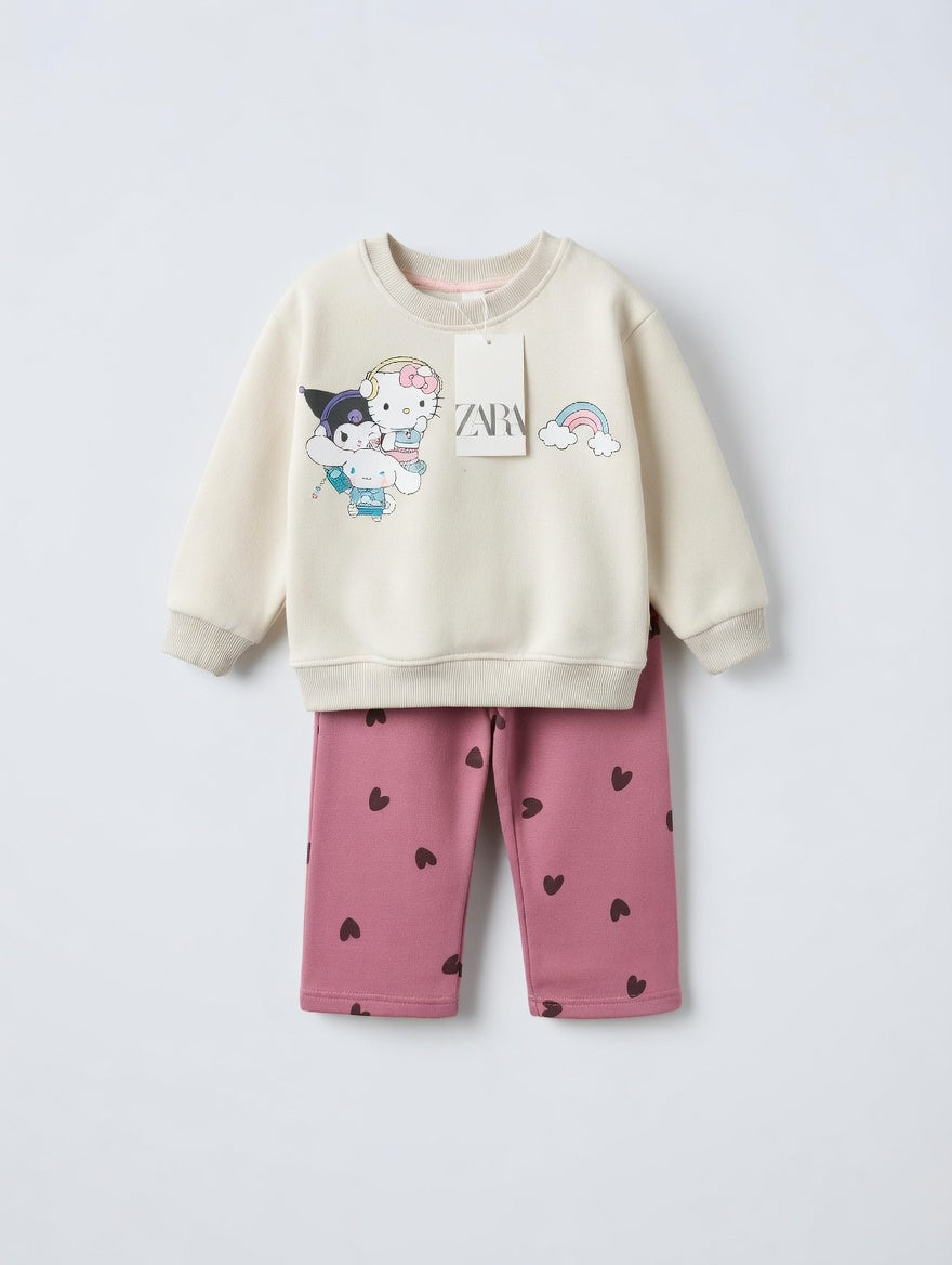 Conjunto EmpiBy de sudadera crema con estampado de Hello Kitty y pantalón rosa viejo con corazones negros para niña