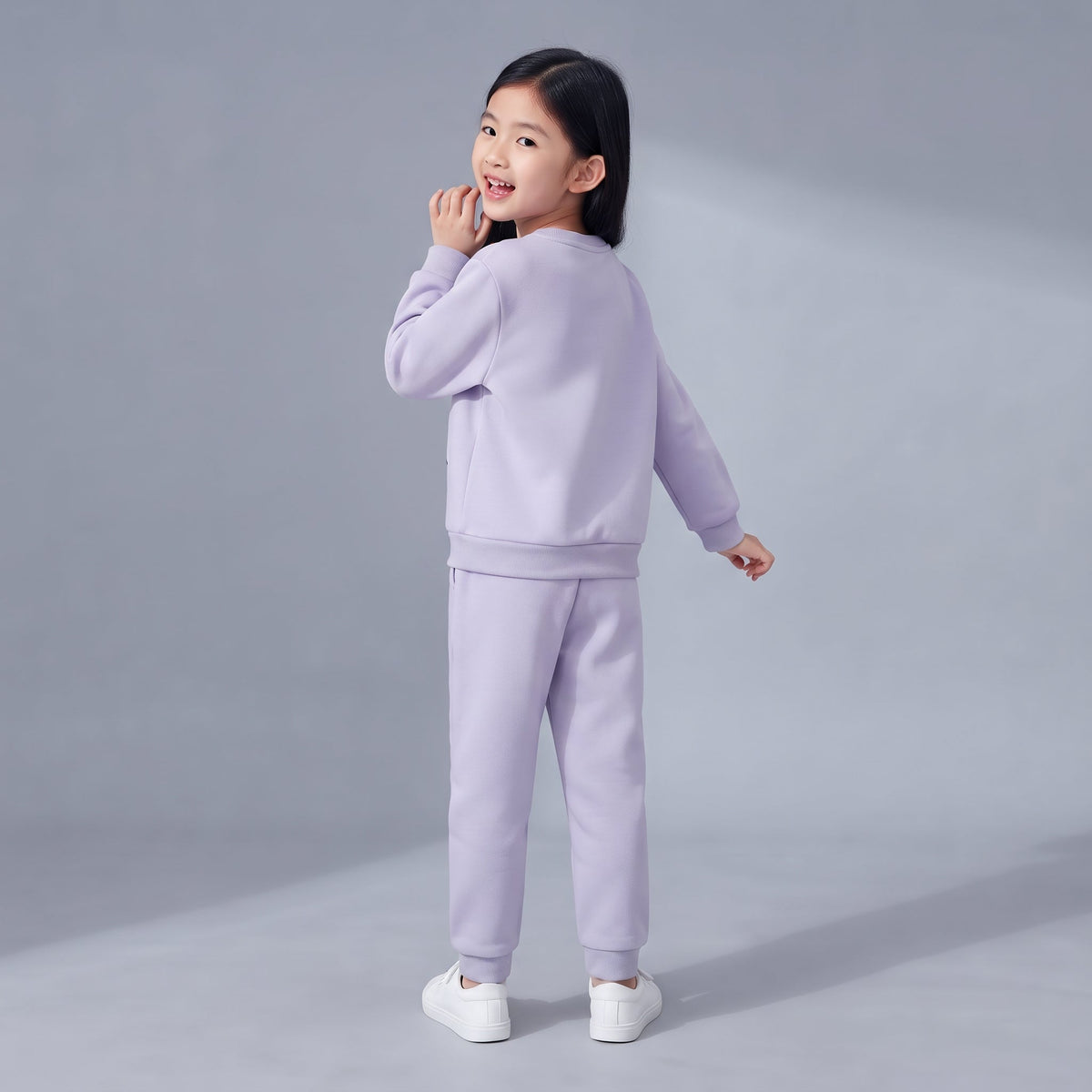 Niña vistiendo conjunto EmpiBy de dos piezas en color lila suave, sudadera y pantalón jogger, vista trasera
