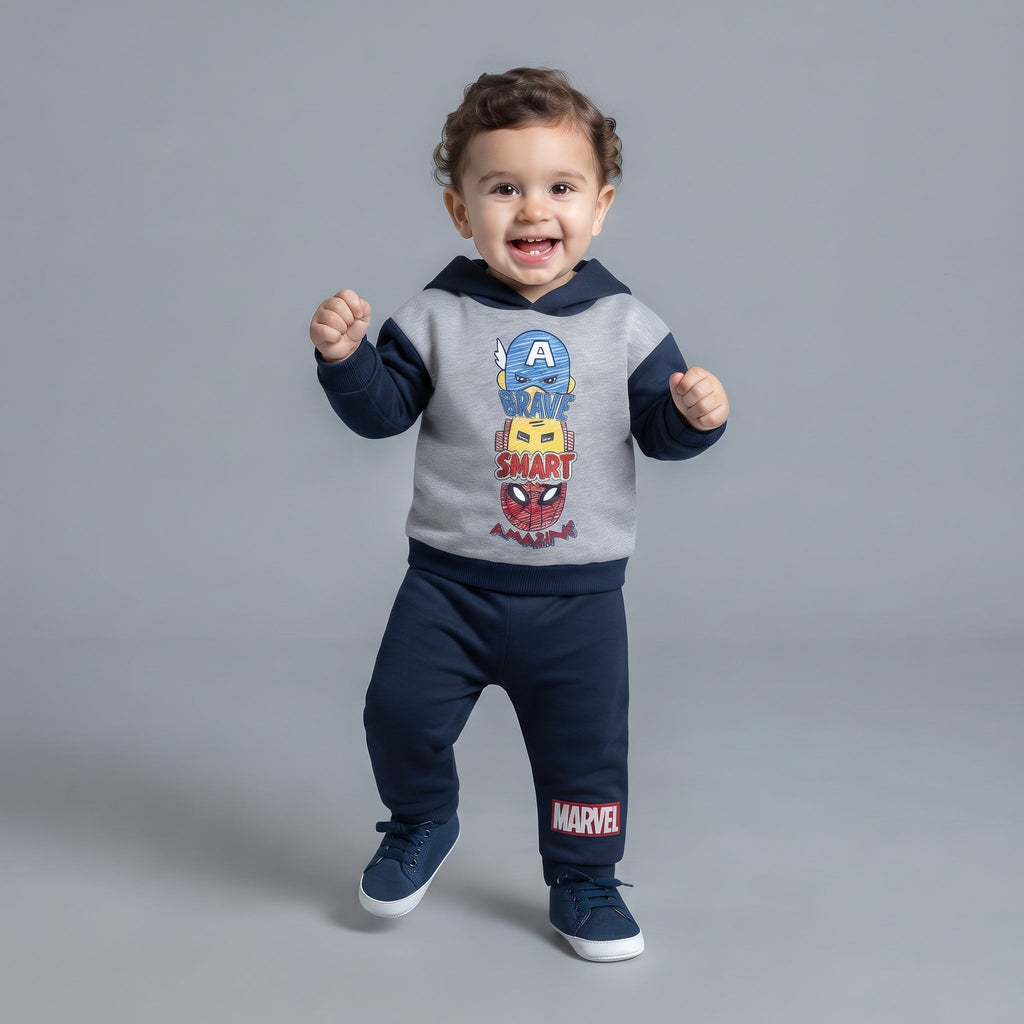 Bebé sonriente con conjunto EmpiBy de Marvel, sudadera gris y azul con héroes y pantalón jogger azul marino