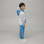 Niño sonriente vistiendo conjunto EmpiBy Marvel con sudadera color block y pantalón azul con estampado de superhéroes
