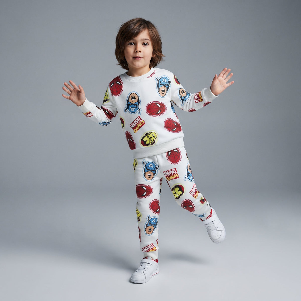 Niño vistiendo conjunto EmpiBy de dos piezas Marvel con estampado de superhéroes sobre fondo blanco y zapatillas