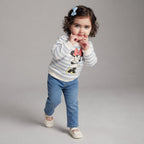 Niña pequeña con conjunto EmpiBy de jeans azules y buso a rayas con estampado de Minnie Mouse y lazo en el cabello