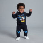 Bebé sonriente vistiendo conjunto EmpiBy de sudadera con capucha y jogger azul marino con estampado de Mickey Mouse