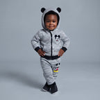 Bebé sonriente vistiendo conjunto EmpiBy de Mickey Mouse gris jaspeado con sudadera de orejitas y pantalón jogger