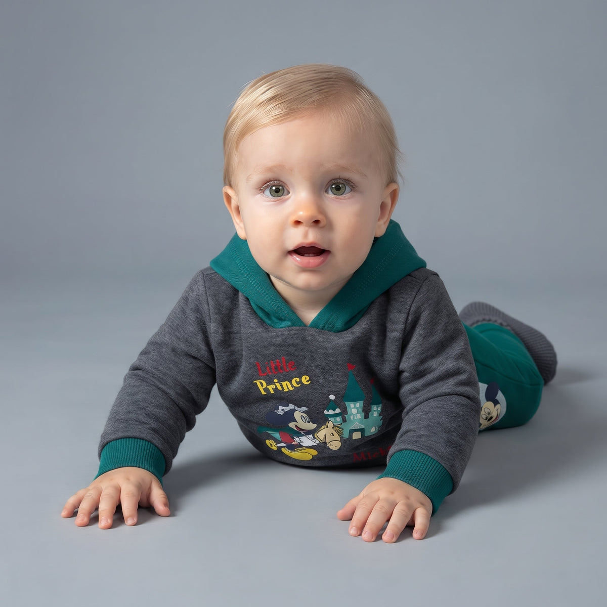 Bebé con conjunto EmpiBy de dos piezas, sudadera gris con Mickey Mouse y pantalón jogger verde esmeralda.