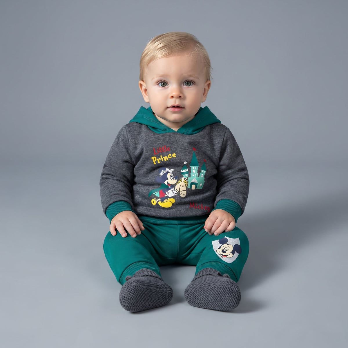 Bebé con conjunto EmpiBy de dos piezas: sudadera gris con capucha verde y pantalón jogger verde de Mickey Mouse.
