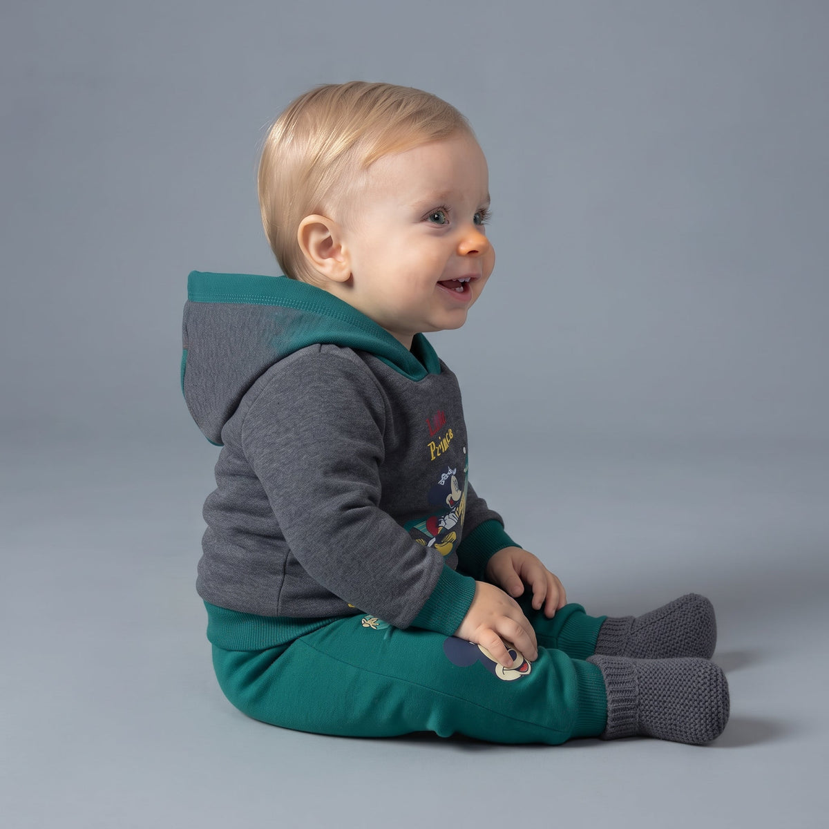 Bebé con conjunto EmpiBy de dos piezas, sudadera gris con capucha verde y pantalón jogger verde de Mickey Mouse
